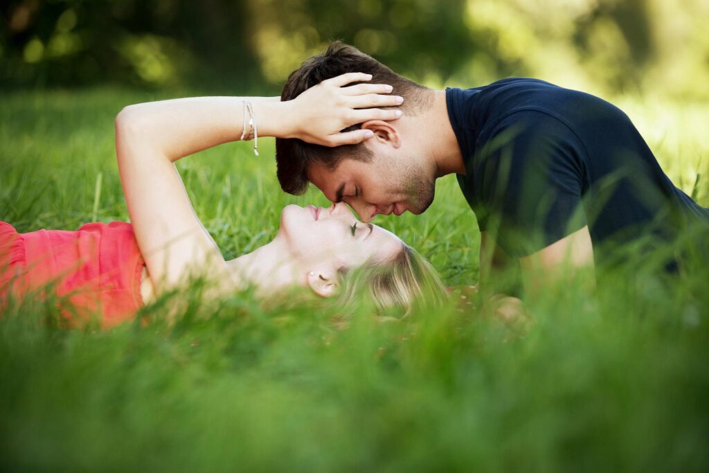 Paar liegt glücklich auf einer Wiese und schaut sich in die Augen. Eine glückliche Paarbeziehung muss kein Oxymoron - Widerspruch sein.