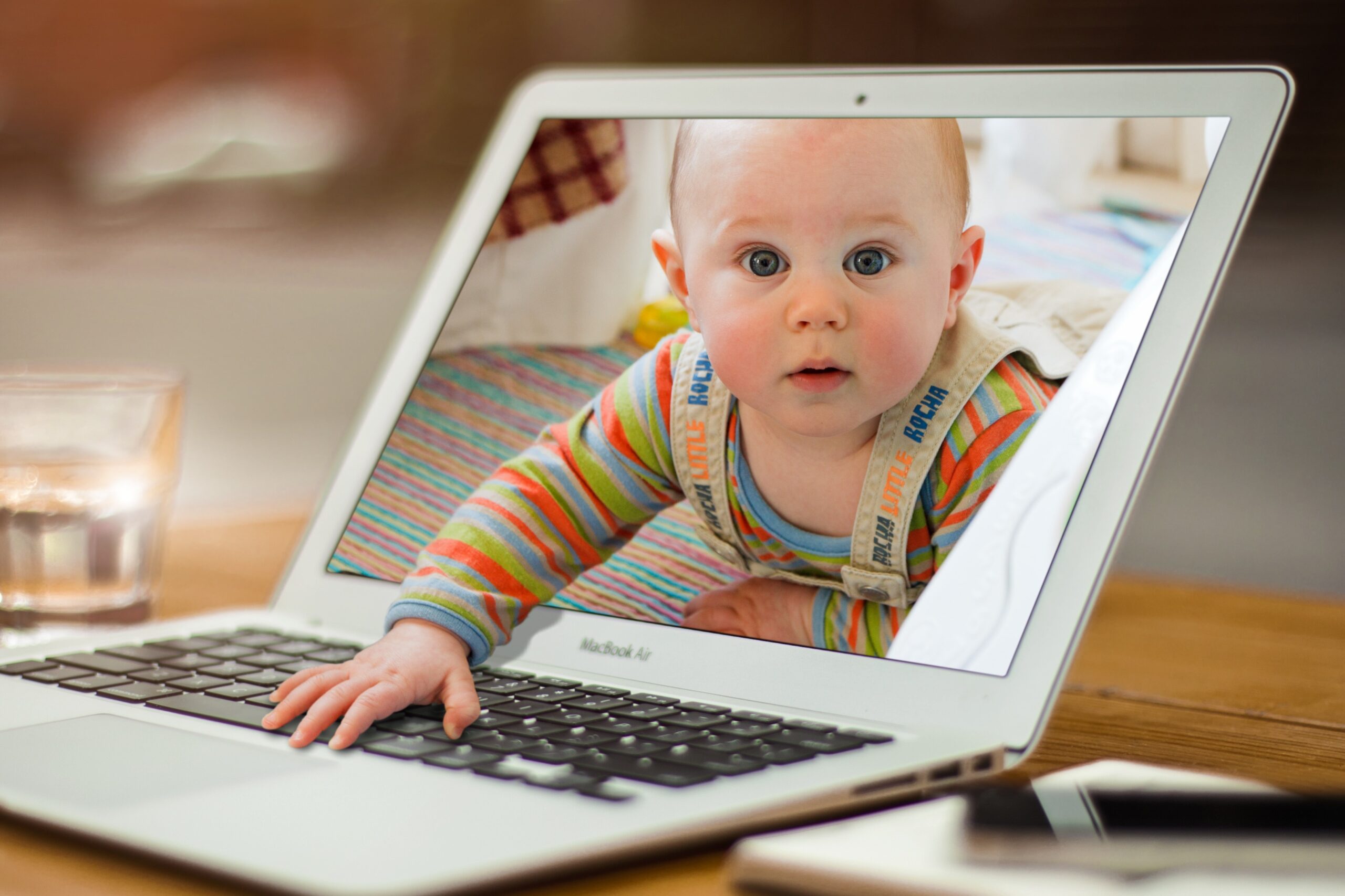 Ein Kind scheint aus dem Monitor eines Laptops herauszukrabbeln. Es sucht Beachtung da es von den Eltern allzuoft nur den Rücken oder das Smartphone kennt!