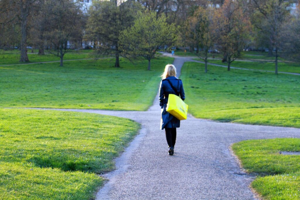 Eine Frau spaziert durch einen Park, der ihr verschiedene Wege anbietet. Resilienz ist ein Spaziergang voller Möglichkeiten