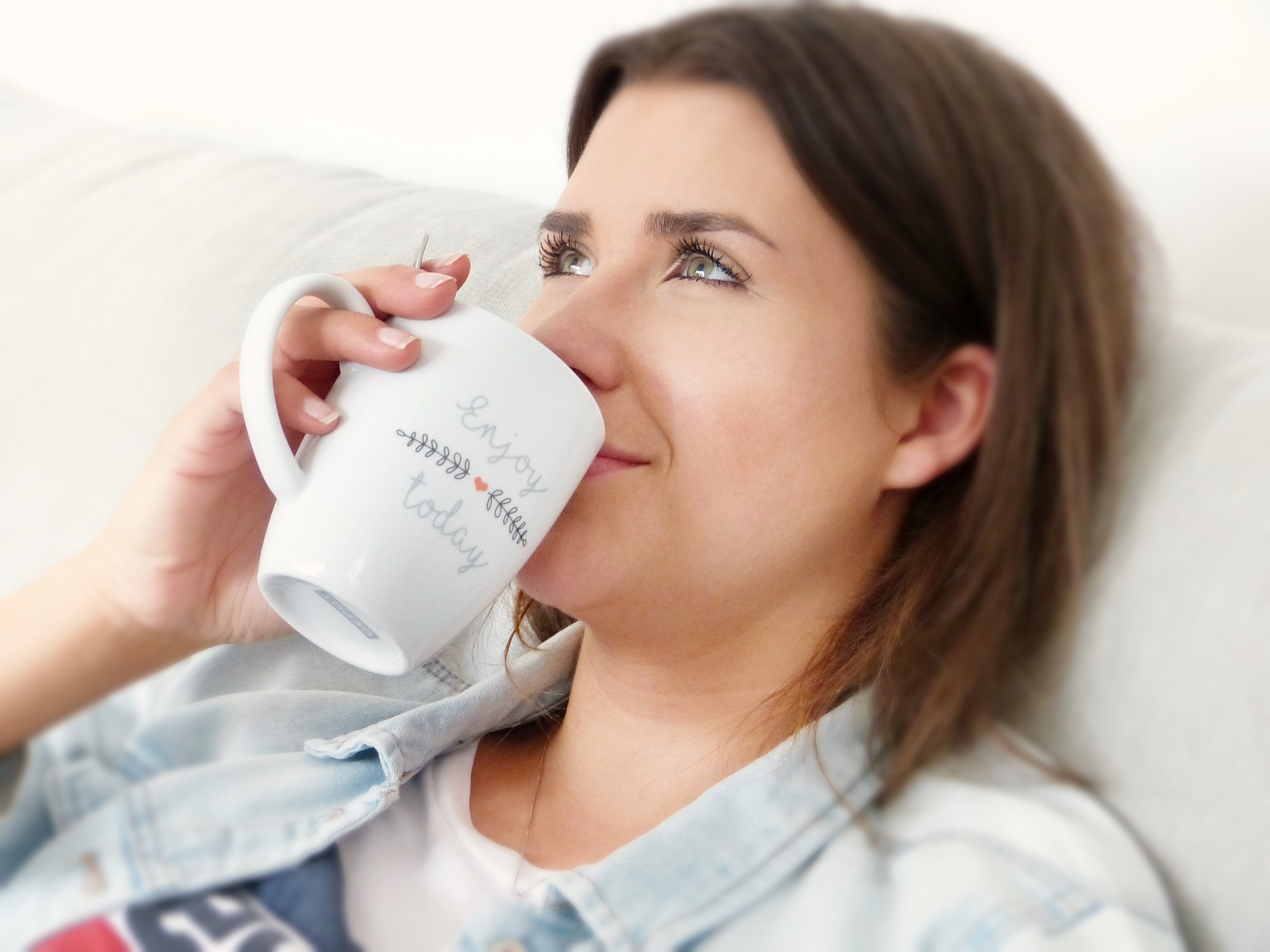 eine Frau trinkt entspannt auf einem Sofa ihren Kaffee. Man nennt es Achtsamkeit. Nennt man es Schneckenhaus ist es gleich negativ. Vielleicht ist es aber umso nötiger.