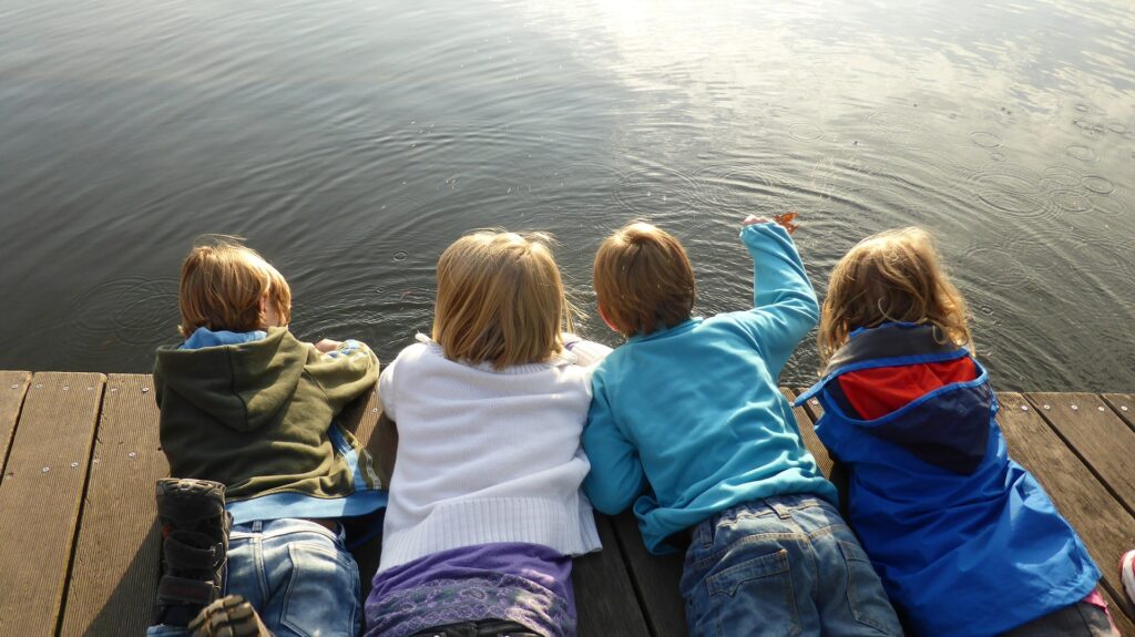 Kinder liegen auf den Boden am einem Berg und schauen in die Weite. Beziehungsorientierung lässt uns gemeinsam blicken.