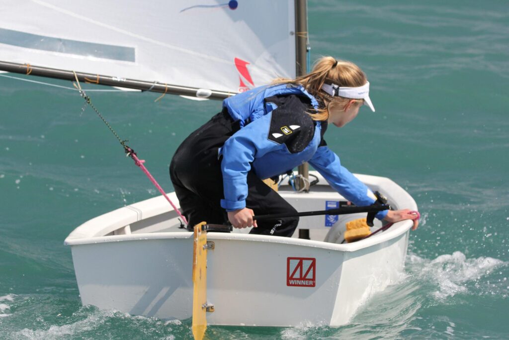 eine Frau segelt voller Zuversicht und Freude mit ihrem Boot. Optimismus ist ein Wirkfaktor der Resilienz!