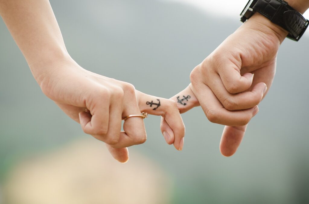 Mann und Frau haken sich mit jeweils einem Finger ein. Beide haben einen Anker tätowiert. Einmal mehr Versöhnung suchen.
